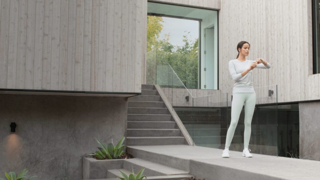 Savant Interfaces: #1 Intelligent Design 6 a woman standing on stairs outside a building checking on her Savant system to turn off all the devices