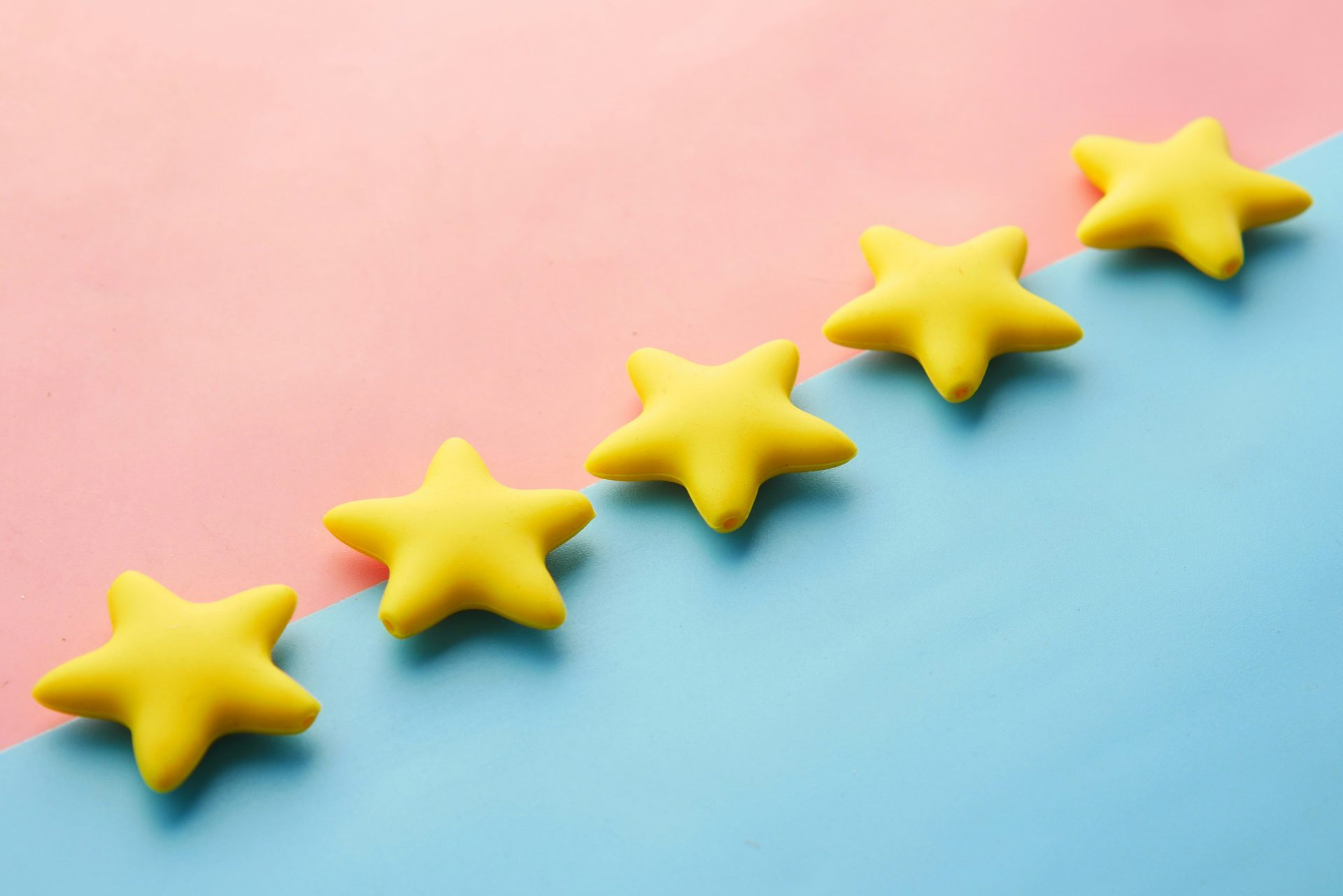Five yellow star-shaped objects are arranged diagonally on a pink and blue background.