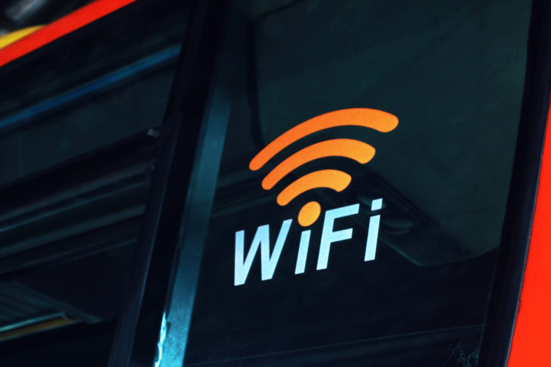 A vibrant orange Wi-Fi symbol and "WiFi" text are visible on a dark, reflective surface, likely a window.